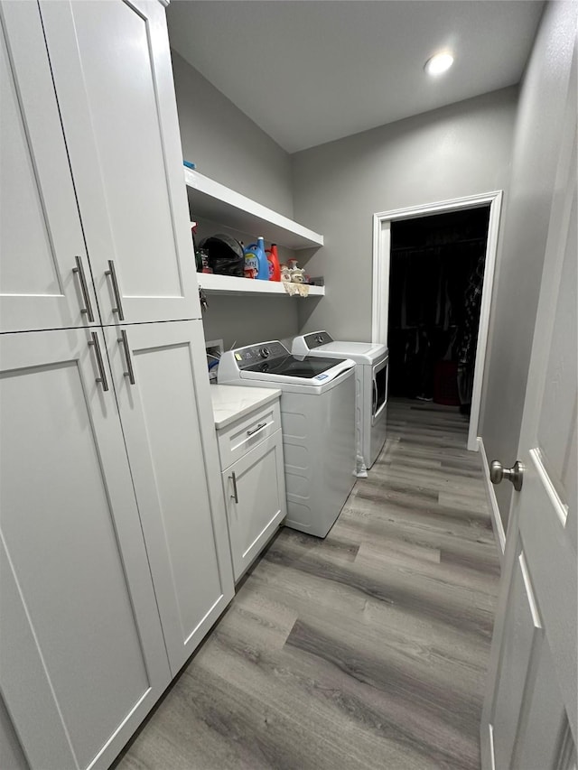 laundry room with washer and clothes dryer, recessed lighting, light wood-type flooring, and cabinet space
