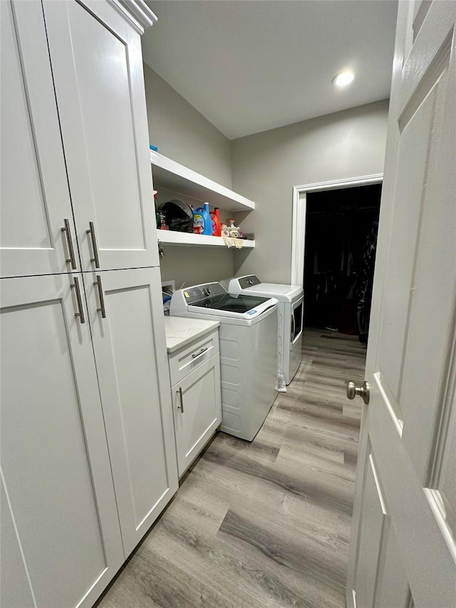 laundry room with cabinet space, washer and clothes dryer, recessed lighting, and light wood-style floors