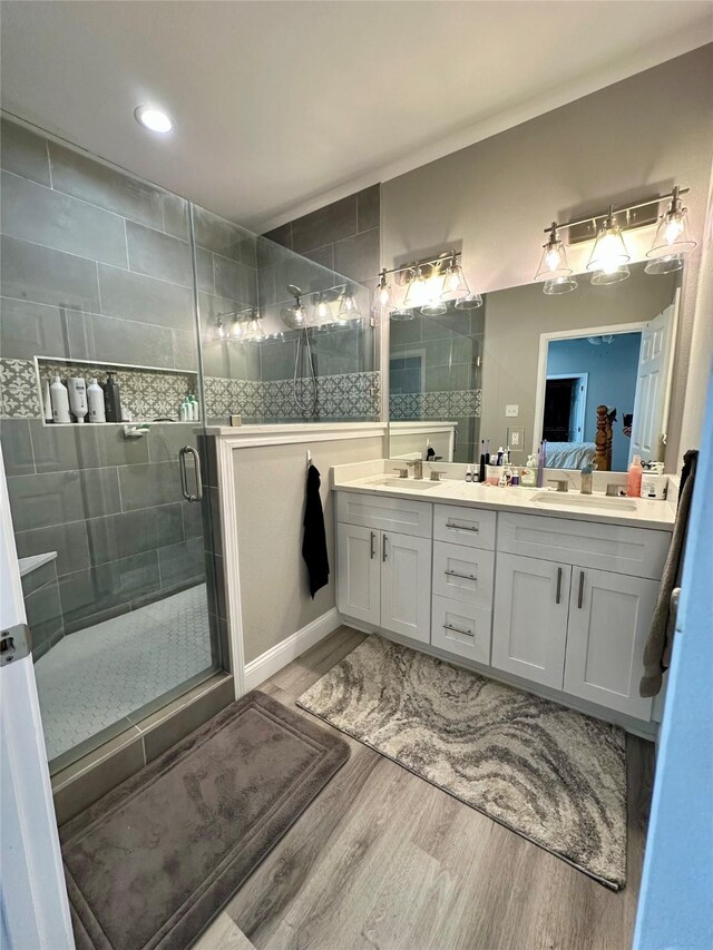 full bath featuring a shower stall, wood finished floors, a sink, and ensuite bath