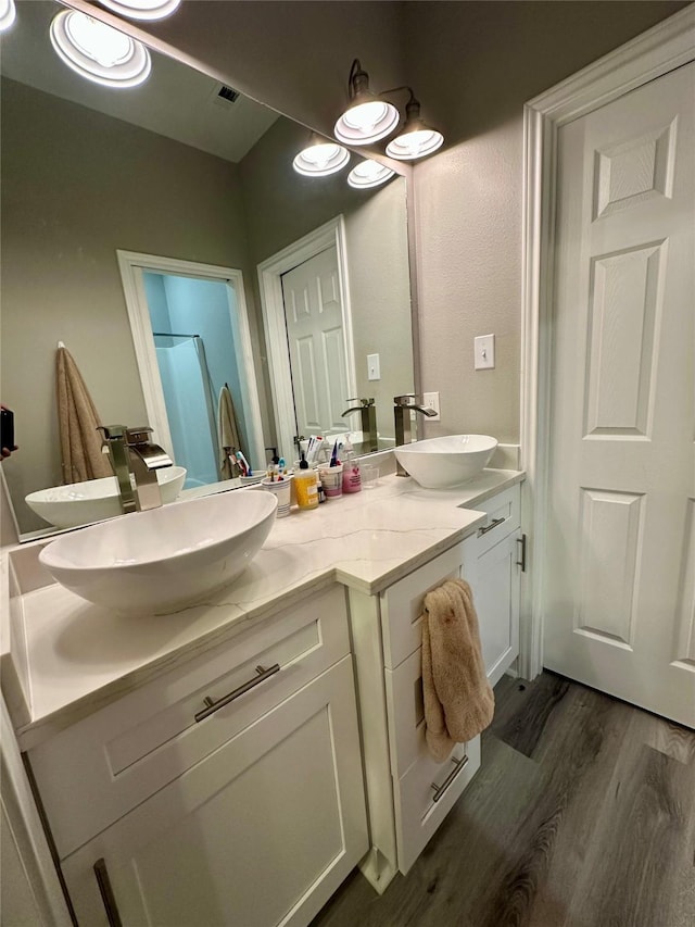 bathroom featuring double vanity, a sink, and wood finished floors