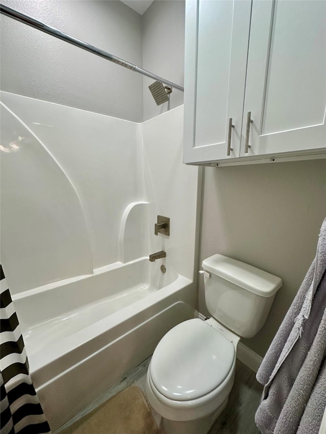 full bathroom with toilet, shower / bath combo, wood finished floors, and baseboards