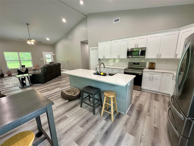 kitchen featuring white cabinets, high vaulted ceiling, visible vents, and stainless steel appliances