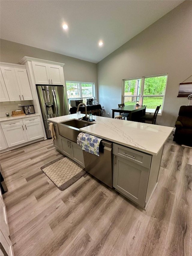 kitchen featuring white cabinets, a sink, lofted ceiling, stainless steel appliances, and light wood finished floors