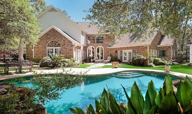 38 Southgate Dr, The Woodlands, TX 77380 - back of house with a shingled roof, an outdoor pool, a patio area, brick siding, and french doors