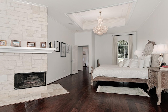 38 Southgate Dr, The Woodlands, TX 77380 - bedroom featuring an inviting chandelier, a stone fireplace, crown molding, a tray ceiling, and hardwood / wood-style floors