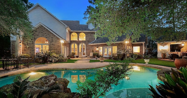 38 Southgate Dr, The Woodlands, TX 77380 - rear view of house featuring a patio area, brick siding, french doors, and an outdoor pool
