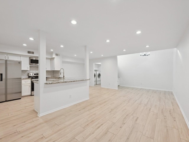 1812 Saxony Ln, Houston, TX 77058 - kitchen featuring appliances with stainless steel finishes, washer and dryer, white cabinets, a sink, and light wood finished floors