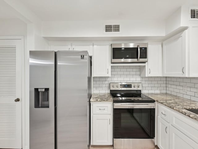 1812 Saxony Ln, Houston, TX 77058 - kitchen with appliances with stainless steel finishes, white cabinets, tasteful backsplash, and light stone countertops