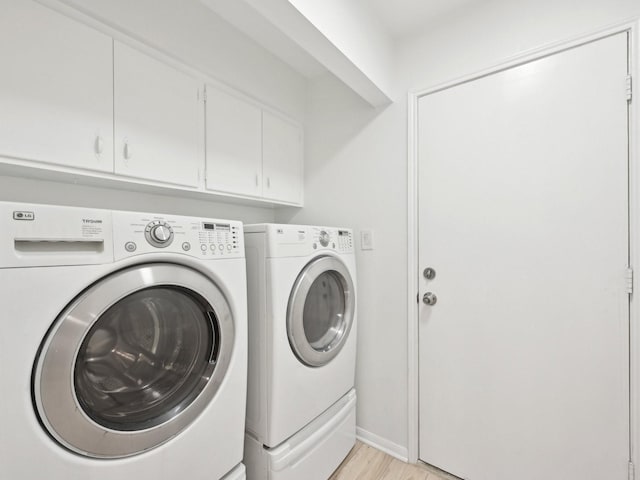 1812 Saxony Ln, Houston, TX 77058 - laundry room featuring washer and clothes dryer, cabinet space, and light wood-style floors