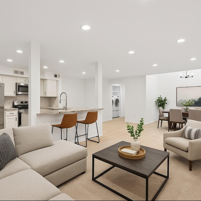 1812 Saxony Ln, Houston, TX 77058 - living area with recessed lighting, washer and dryer, baseboards, a chandelier, and light wood-style flooring