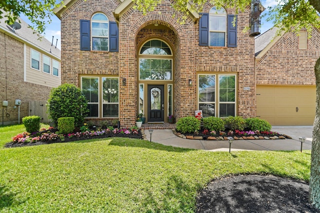 traditional home with concrete driveway, a front yard, brick siding, and a garage