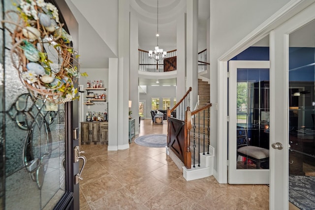 entrance foyer with a towering ceiling, stairs, a notable chandelier, and a wealth of natural light