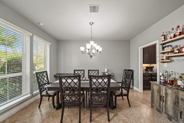 dining room featuring light tile patterned floors, a notable chandelier, visible vents, baseboards, and a dry bar