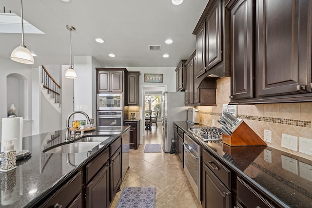 kitchen with dark stone counters, a sink, dark brown cabinetry, visible vents, and appliances with stainless steel finishes