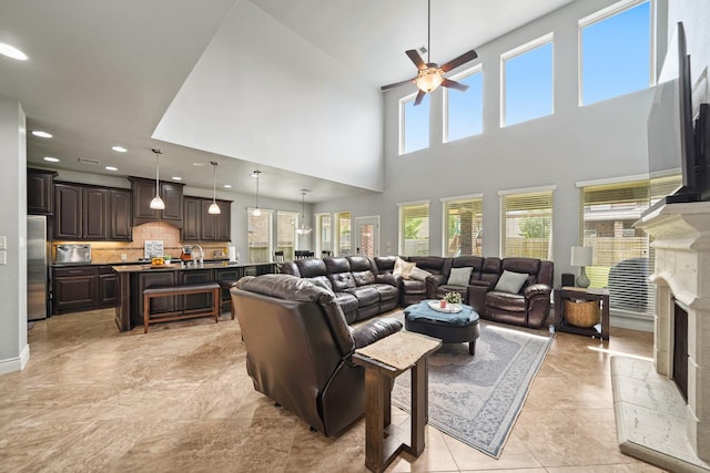 living area with recessed lighting, ceiling fan, a fireplace, and a towering ceiling
