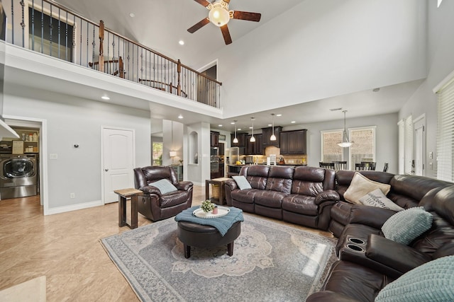 living area with a wealth of natural light, washer / dryer, ceiling fan, and a towering ceiling
