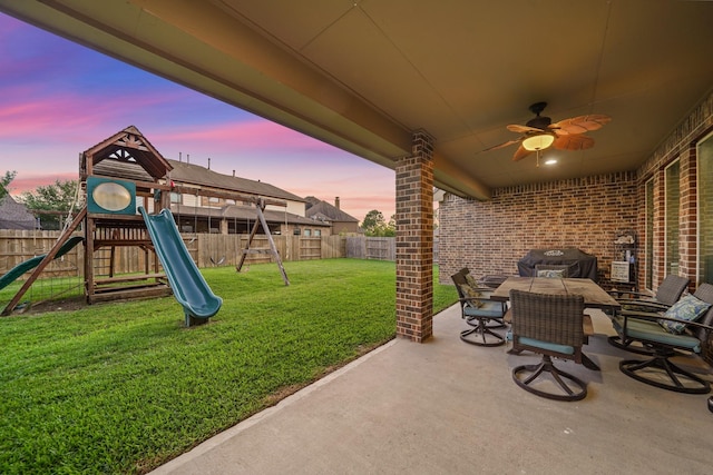 view of patio / terrace with grilling area, a ceiling fan, a playground, and a fenced backyard