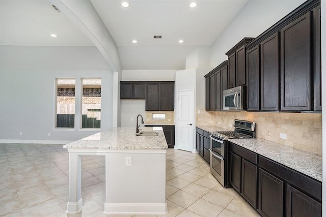 4813 Loures Ln, League City, TX 77573 - kitchen with light stone counters, decorative backsplash, a kitchen island with sink, appliances with stainless steel finishes, and visible vents