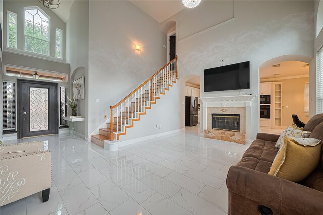 11423 Corola Trail Dr, Houston, TX 77066 - living room with marble finish flooring, high vaulted ceiling, arched walkways, a tiled fireplace, and stairway