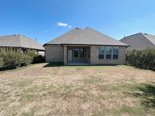 24410 Bludana Ln, Richmond, TX 77406 - back of house featuring roof with shingles, a patio, brick siding, and a lawn