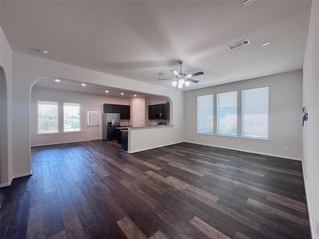 24410 Bludana Ln, Richmond, TX 77406 - unfurnished living room featuring arched walkways, visible vents, ceiling fan, and dark wood finished floors