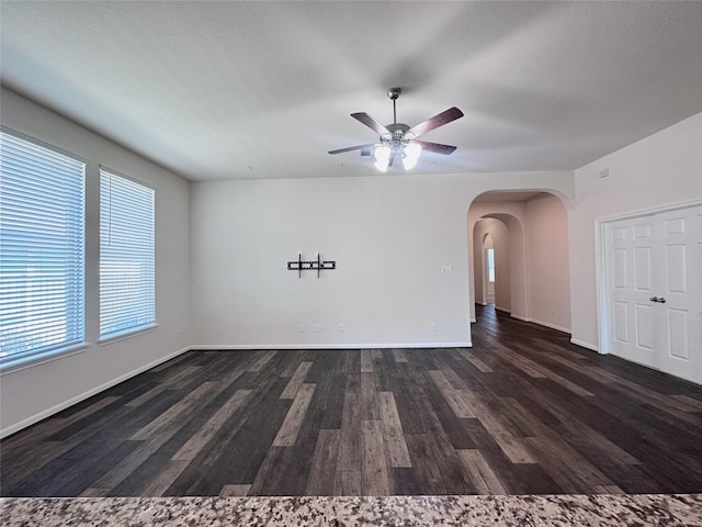 24410 Bludana Ln, Richmond, TX 77406 - unfurnished living room featuring arched walkways, dark wood-style flooring, baseboards, and a ceiling fan