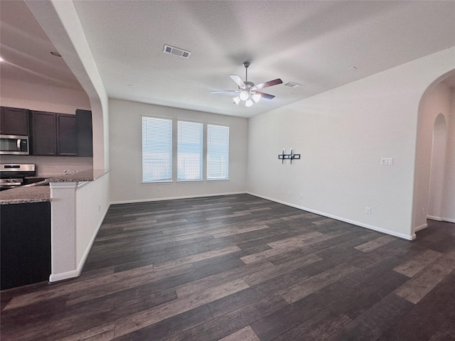 24410 Bludana Ln, Richmond, TX 77406 - unfurnished living room with arched walkways, ceiling fan, dark wood-style floors, and visible vents