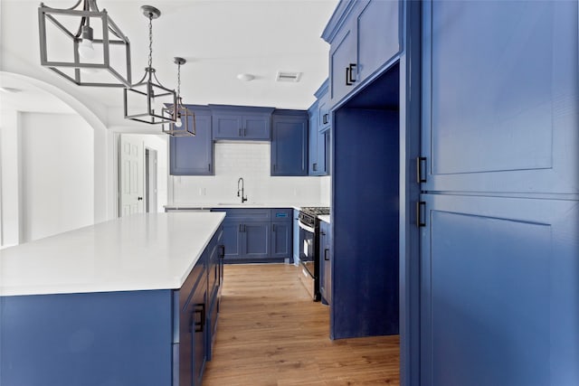 kitchen with gas range, a sink, and blue cabinetry