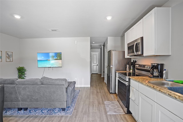 kitchen with light wood-type flooring, open floor plan, white cabinetry, visible vents, and stainless steel appliances