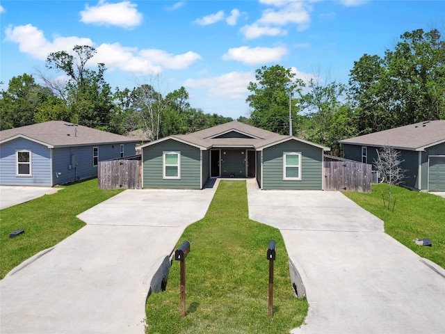 view of front of home with concrete driveway, fence, and a front lawn