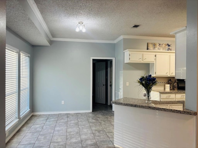 kitchen featuring a textured ceiling, dark stone counters, crown molding, and white cabinetry