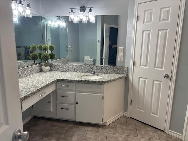 bathroom featuring tile patterned flooring, vanity, baseboards, and toilet