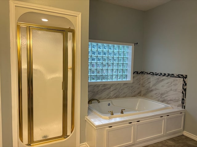 bathroom with a shower stall, a garden tub, and baseboards