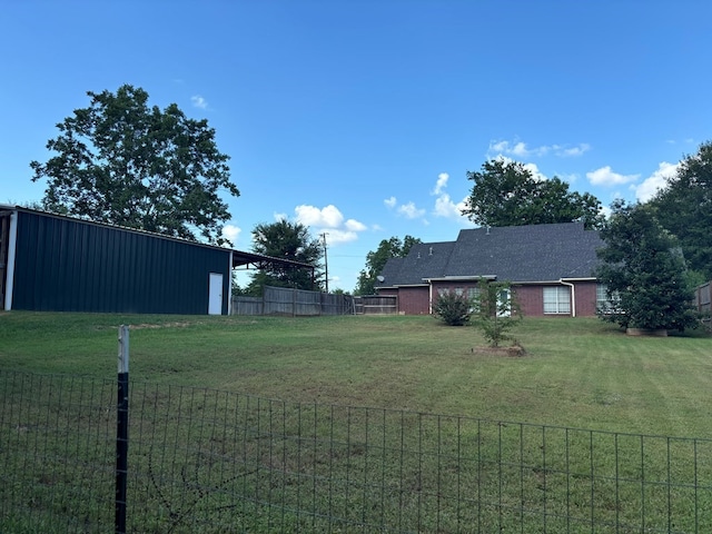 view of yard with fence, an outdoor structure, and a pole building
