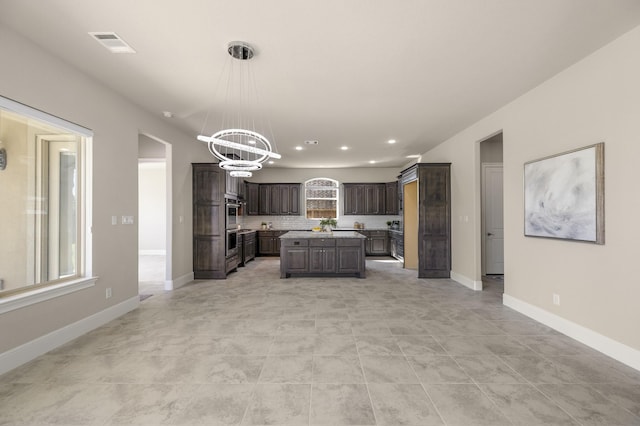 26406 Crimson Bluff Ln, Katy, TX 77494 - kitchen featuring dark brown cabinetry, a notable chandelier, light countertops, a kitchen island, and visible vents