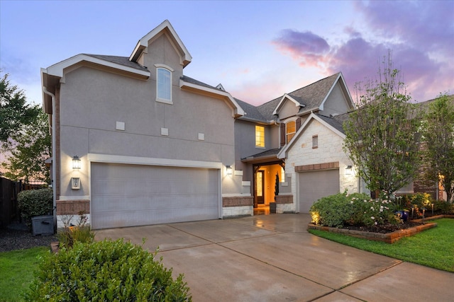 view of front of house featuring a garage, stucco siding, driveway, and stone siding
