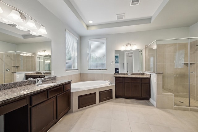 bathroom with a sink, a raised ceiling, tile patterned flooring, a shower stall, and a bath