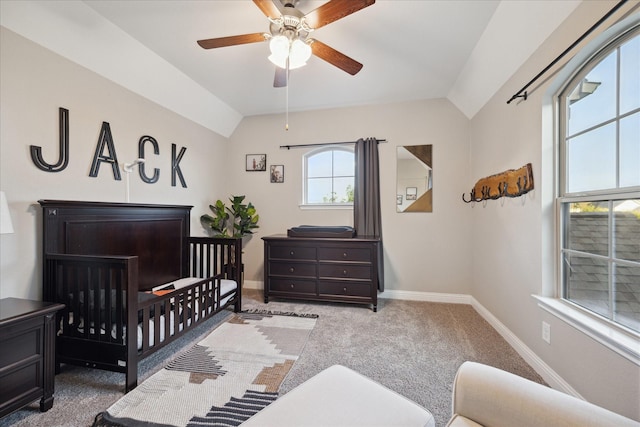 carpeted bedroom featuring baseboards, a ceiling fan, vaulted ceiling, and a crib