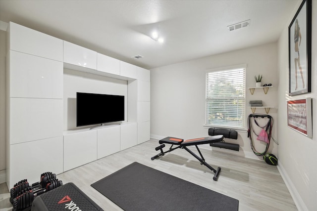 exercise area with visible vents, baseboards, and light wood-type flooring