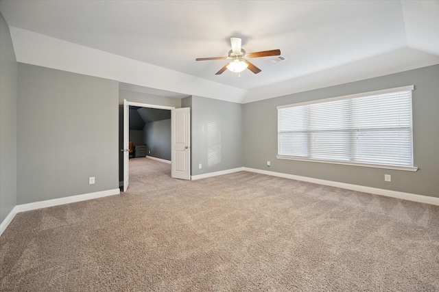 empty room with baseboards, a ceiling fan, vaulted ceiling, and light colored carpet