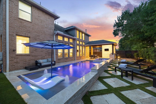 back of property at dusk with a patio, a fenced backyard, brick siding, an outdoor living space, and a fenced in pool