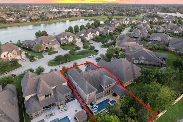 aerial view at dusk with a residential view and a water view