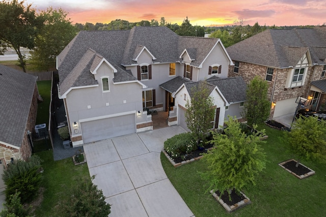 view of front facade featuring a shingled roof, concrete driveway, stucco siding, and a front yard