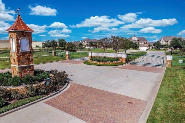 view of home's community featuring fence, curved driveway, a gate, a lawn, and a residential view