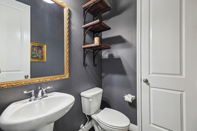 bathroom with baseboards, a sink, a textured wall, and toilet