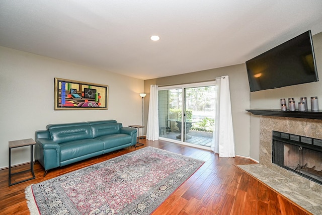 living area with a tiled fireplace, baseboards, recessed lighting, and wood finished floors