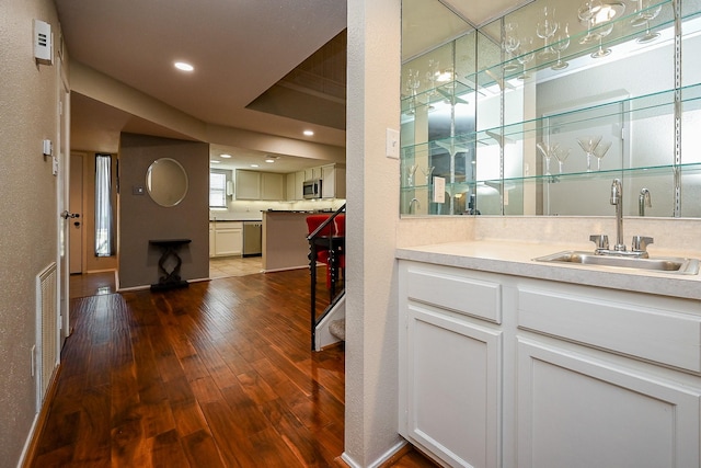 bar featuring indoor wet bar, recessed lighting, a sink, stainless steel appliances, and dark wood-style floors