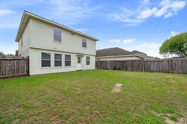 back of property with a fenced backyard and a lawn
