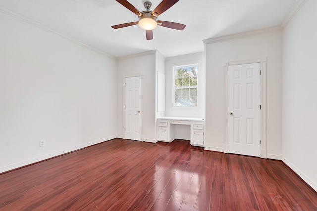 unfurnished bedroom featuring built in study area, dark wood-style floors, ornamental molding, baseboards, and ceiling fan