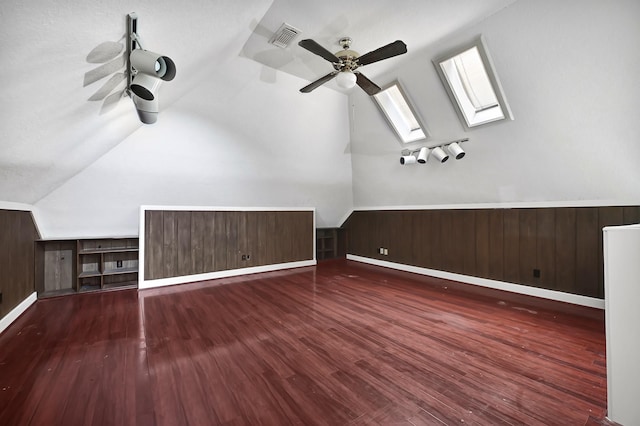 additional living space with lofted ceiling with skylight, visible vents, wood finished floors, and ceiling fan